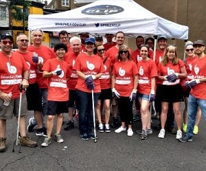 A diverse group of 19 volunteers in red 'bready to text' t-shirts gather under a white tent.